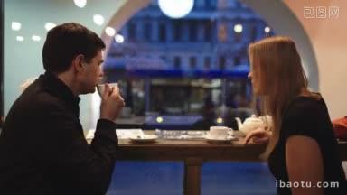 晚上，男人和女人坐在咖啡馆里，一边喝茶，一边谈笑风生